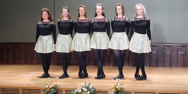 Six Irish dancers from Sound Irish Dance Factory in a dancing pose on stage.