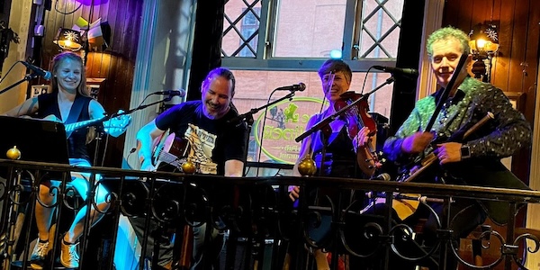 The members of Muintir on stage, smiling, with instruments, at The Dubliner, Oslo
